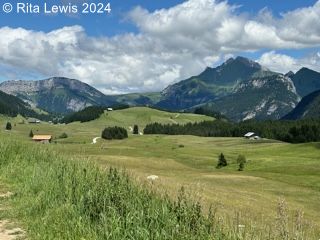 View of flat valley with a farm and mountains in the background