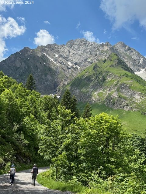 two hikers at lower left setting off to climb the mountain in the distance