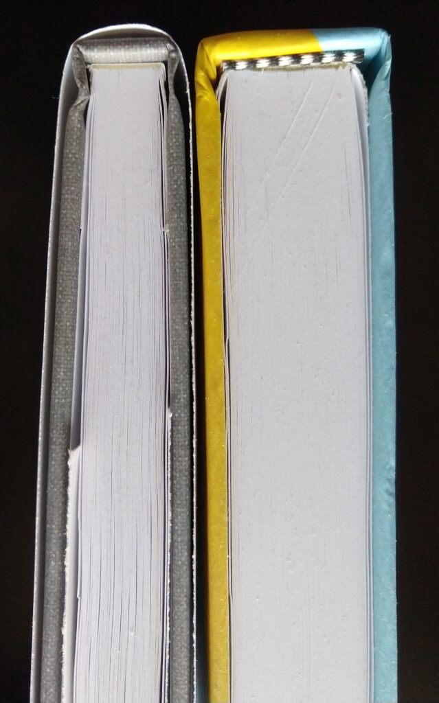 On the left a hardback from IngramSpark in which you can see the "paperback" pasted to the spine. On the right a hardback from KDP in which the glued spine is masked by a striped piece of fabric.