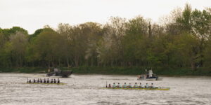 Cambridge and Oxford men's 8 boats racing on April 13 2025. Cambridge is wearing light blue jerseys and is in the lead; Oxford is in dark blue.