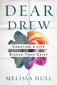 Dear Drew book cover - The background of the cover is a piece of paper that has folds on it as though it has been taken out of an envelope. The title text and author name are in dark blue. The subtitle is black and runs across the central image, which is half a gray-blue funeral-type flower and half a piece of colorful swirled art glass. 